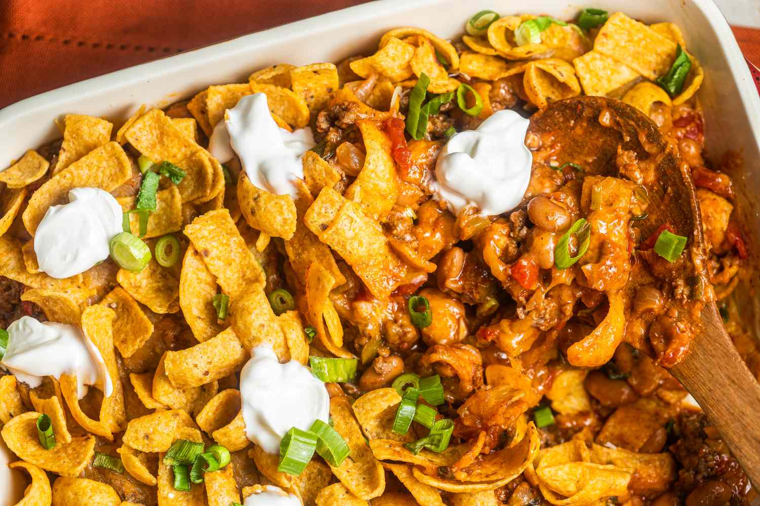 Casserole de tacos à emporter avec des cuillerées de crème aigre dans un plat à gratin avec une cuillère de service (plat à gratin manquant quelques portions)