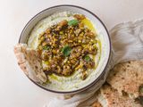 Whipped feta with figs, nuts, and honey in a bowl with bread dipped in the side.