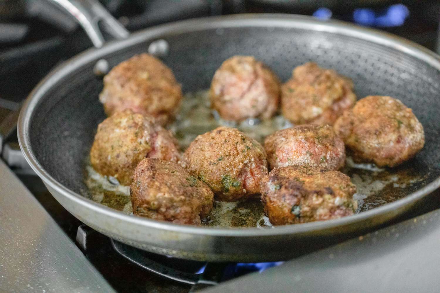 Boulettes de viande en train de se saisir dans une poêle.