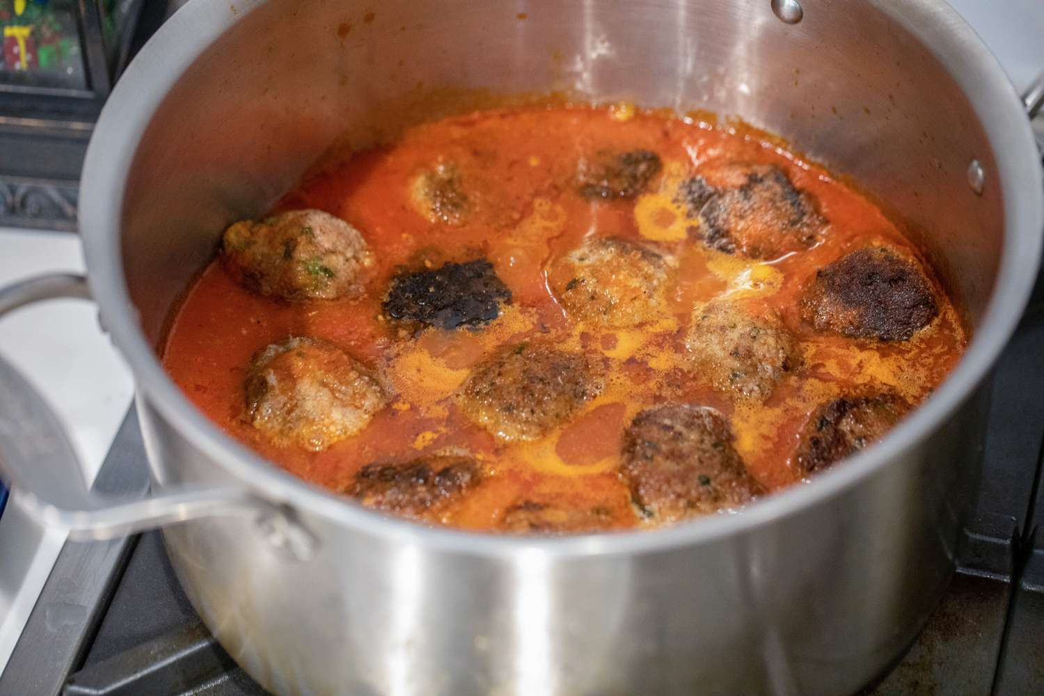 Boulettes de viande en train de cuire dans une casserole de sauce marinara.