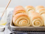 Utah's famous lion house rolls on a baking sheet with a jar of melted butter to the left.