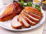 Apple and sage-brined smoked turkey breast sliced on a platter.