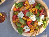 Bowl of Fried Polenta Panzanella with Tomato, Basil, and Burrata with a Drink on a Table