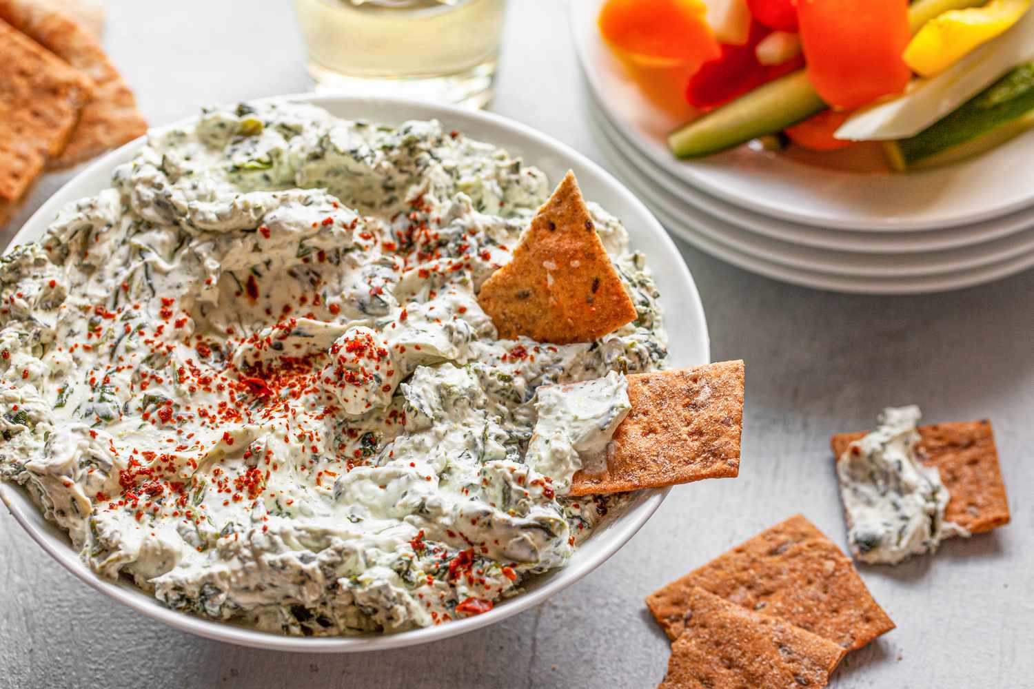 Crackers Dipped into a Bowl of Easy Spinach Dip, Next to Another Bowl of Veggie Strips