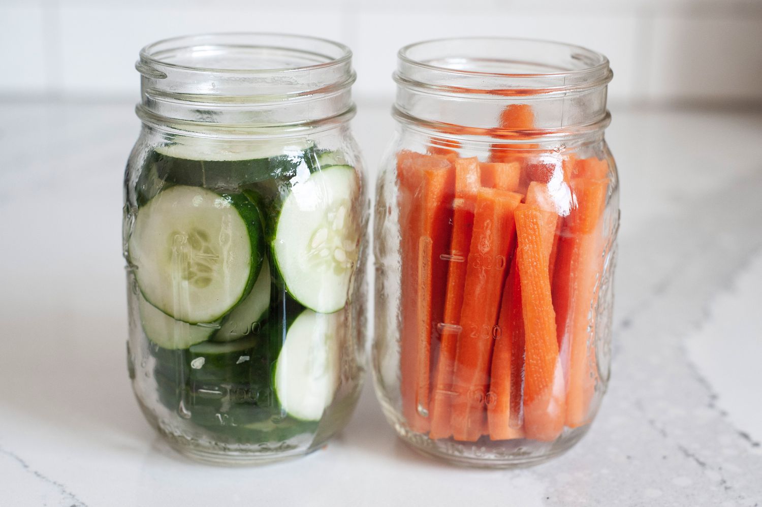 Bocaux de tranches de concombre et de carottes pour la recette de pickles rapides