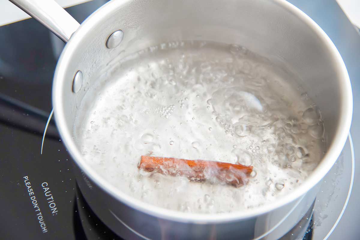 Pan with simmering water and a cinnamon stick inside to make homemade horchata.