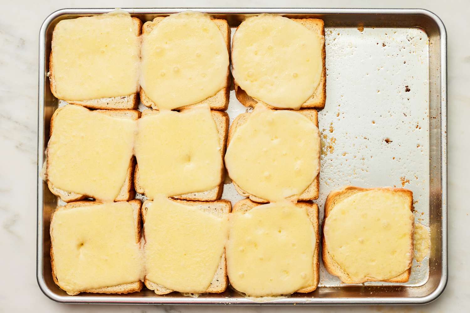 Slightly Melted Cheese Slices on Slices of Bread on the Baking Pan