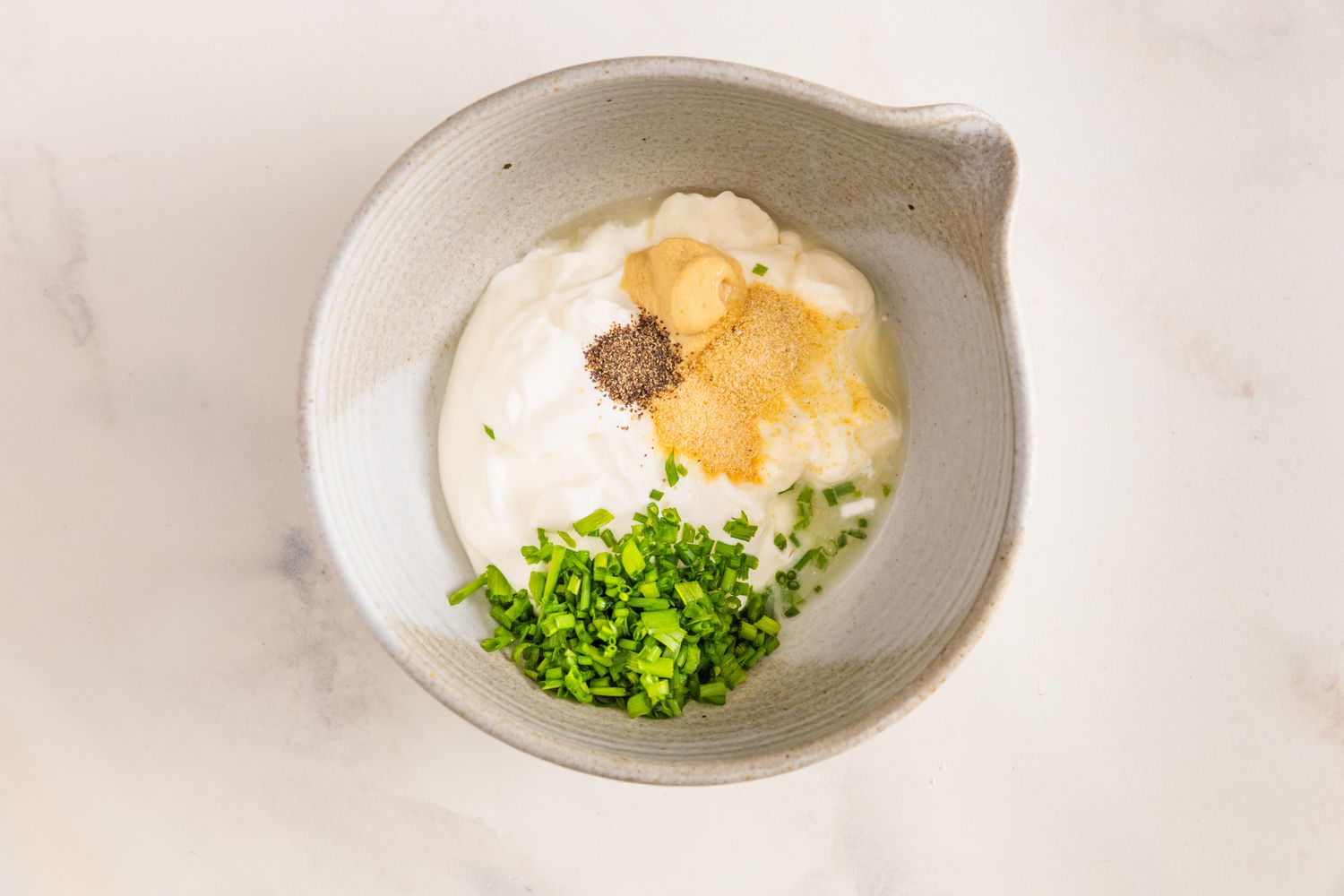 Bol des ingrédients de la vinaigrette à la crème aigre et à l'oignon (crème aigre, ciboulette et épices)