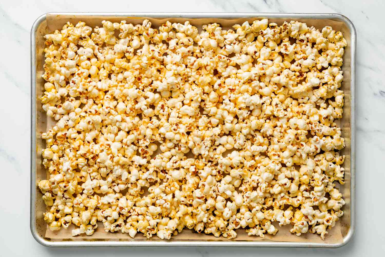 Honey popcorn spread onto the parchment paper lined baking tray (before baking)