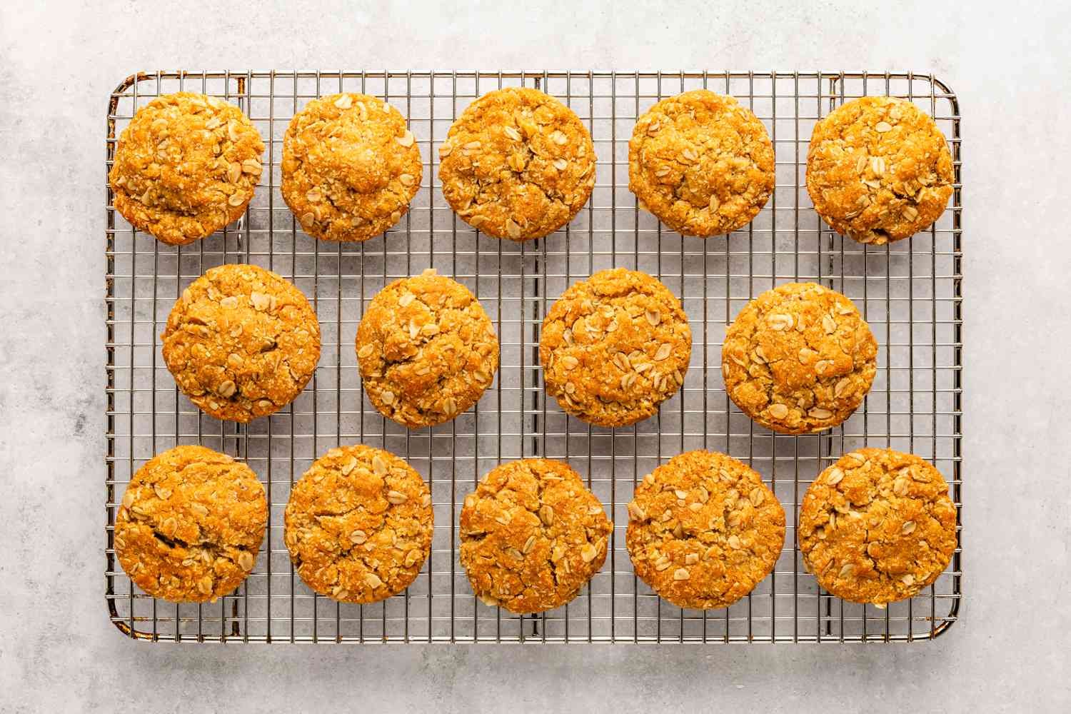 Quatorze biscuits cuits pour la recette des biscuits Anzac refroidissant sur une grille