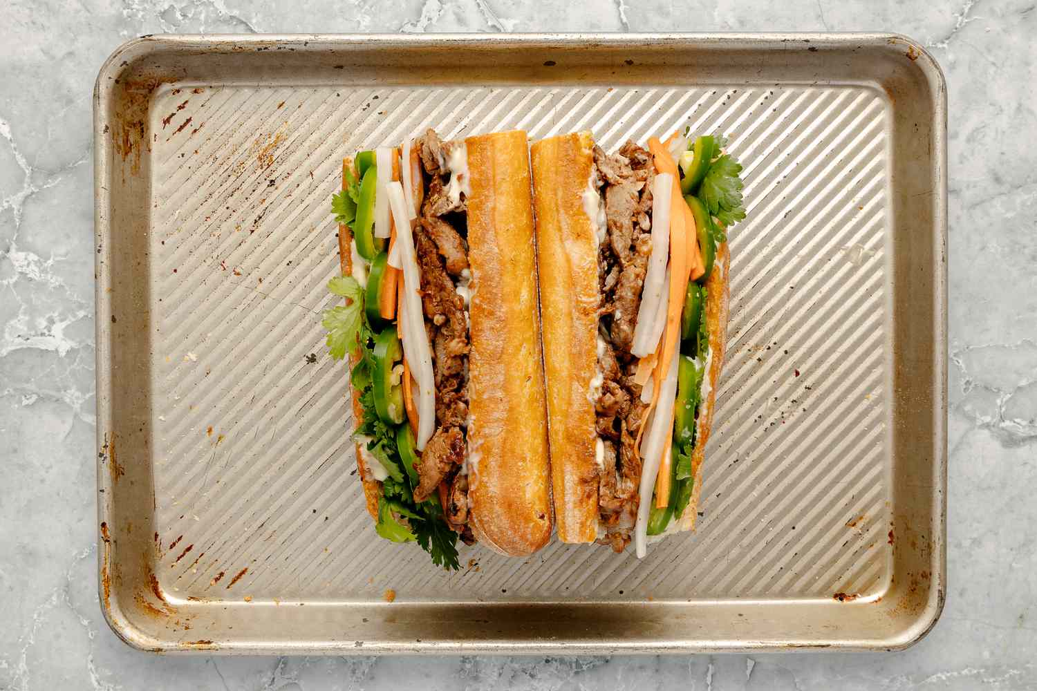 Pork Banh Mi Cut in Half on Baking Sheet