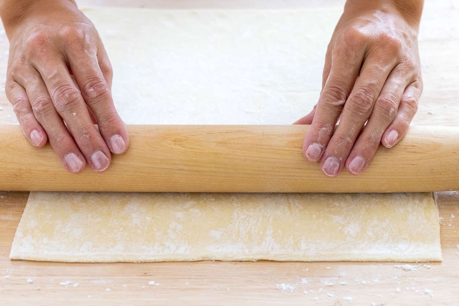 Rolling out puff pastry to make savory pinwheels.