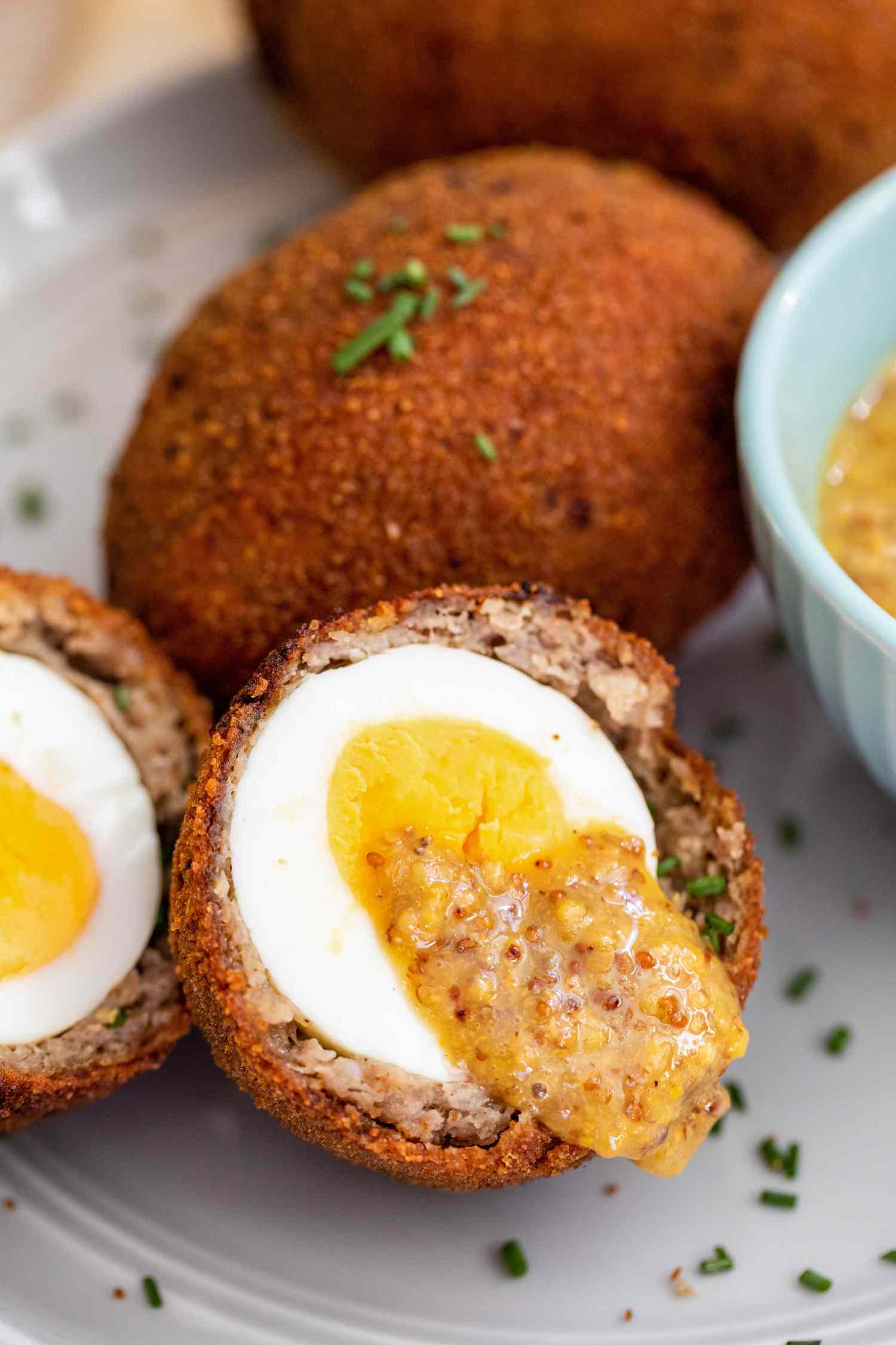 La moitié d'un Scotch egg recouverte de miel-moutarde.