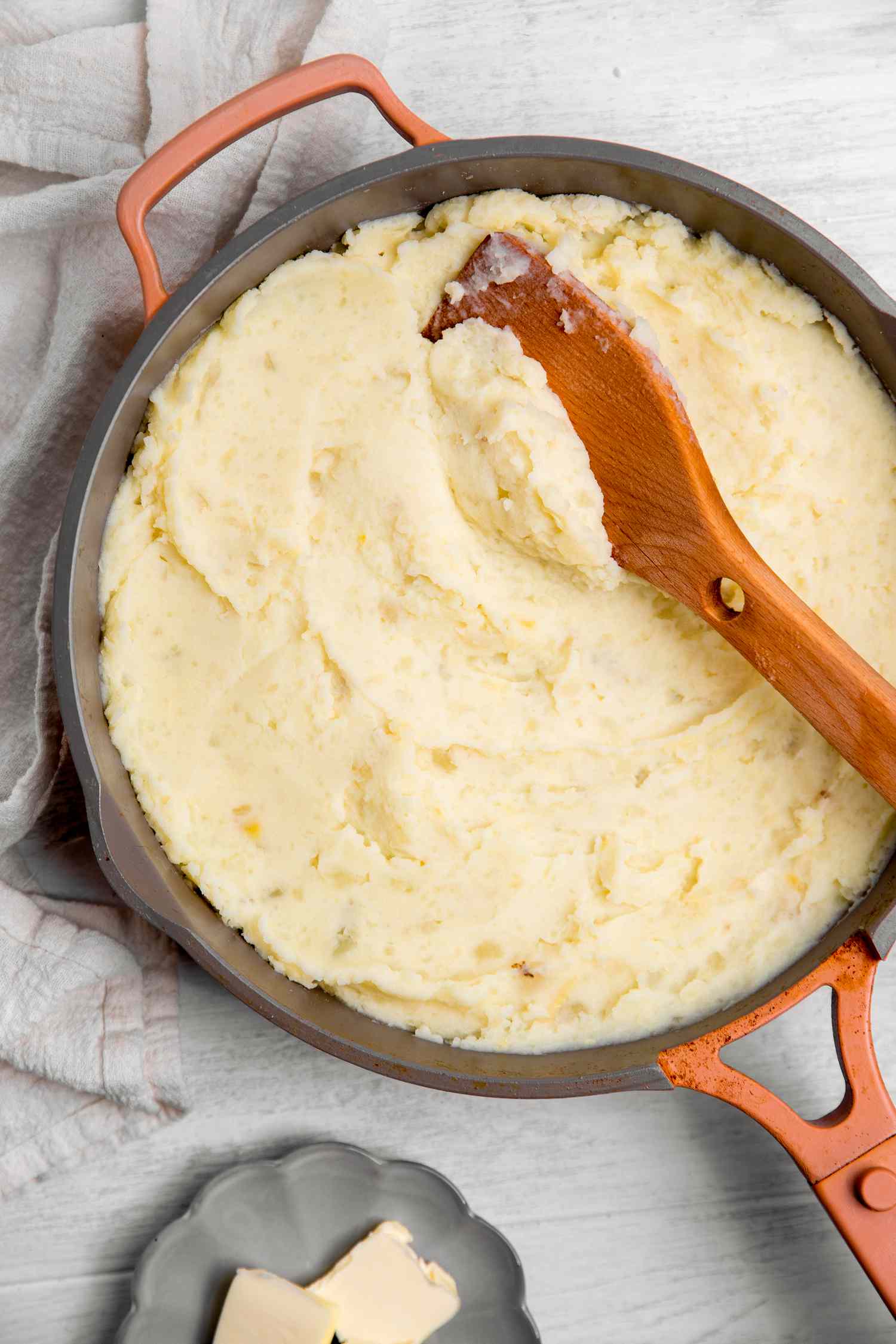 Vegan Mashed Potatoes in a Pot Next to a Saucer of Butter Slices 