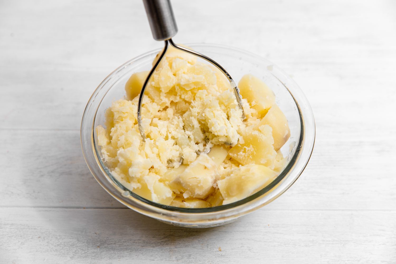 Potatoes Mashed in Bowl Using a Potato Masher