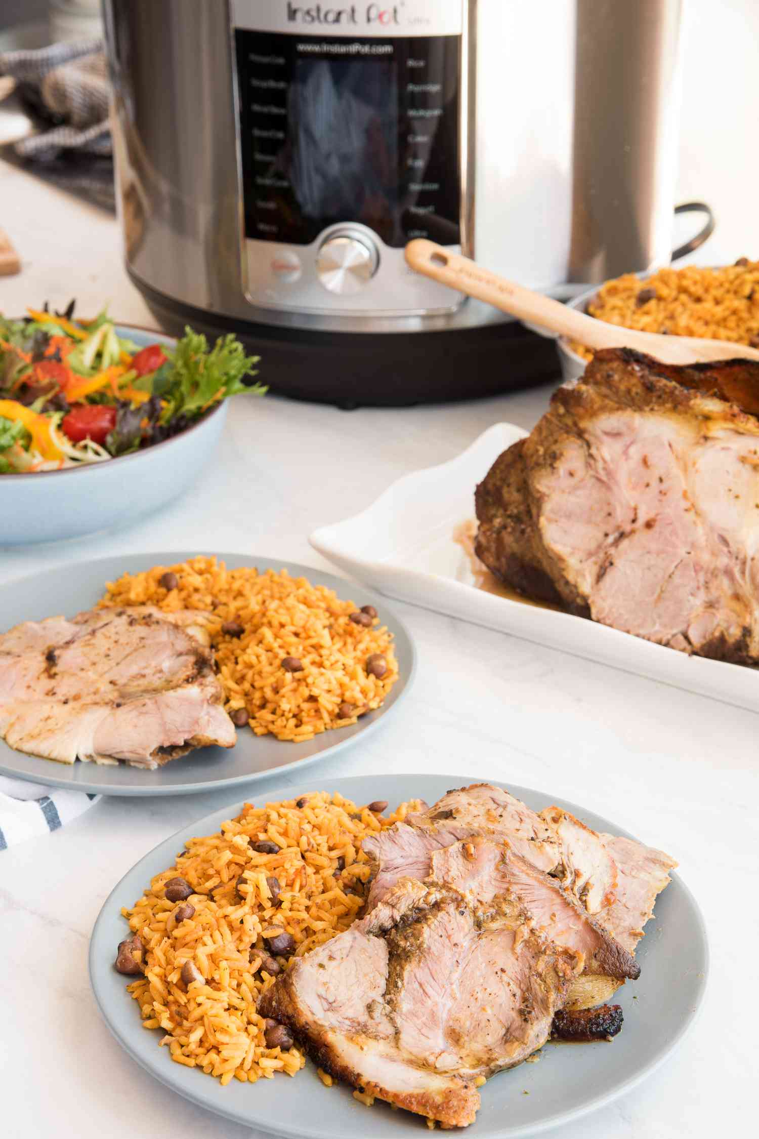 Instant Pot Pernil Served with Rice, and in the Background, More Pernil on a Platter and an Instant Pot