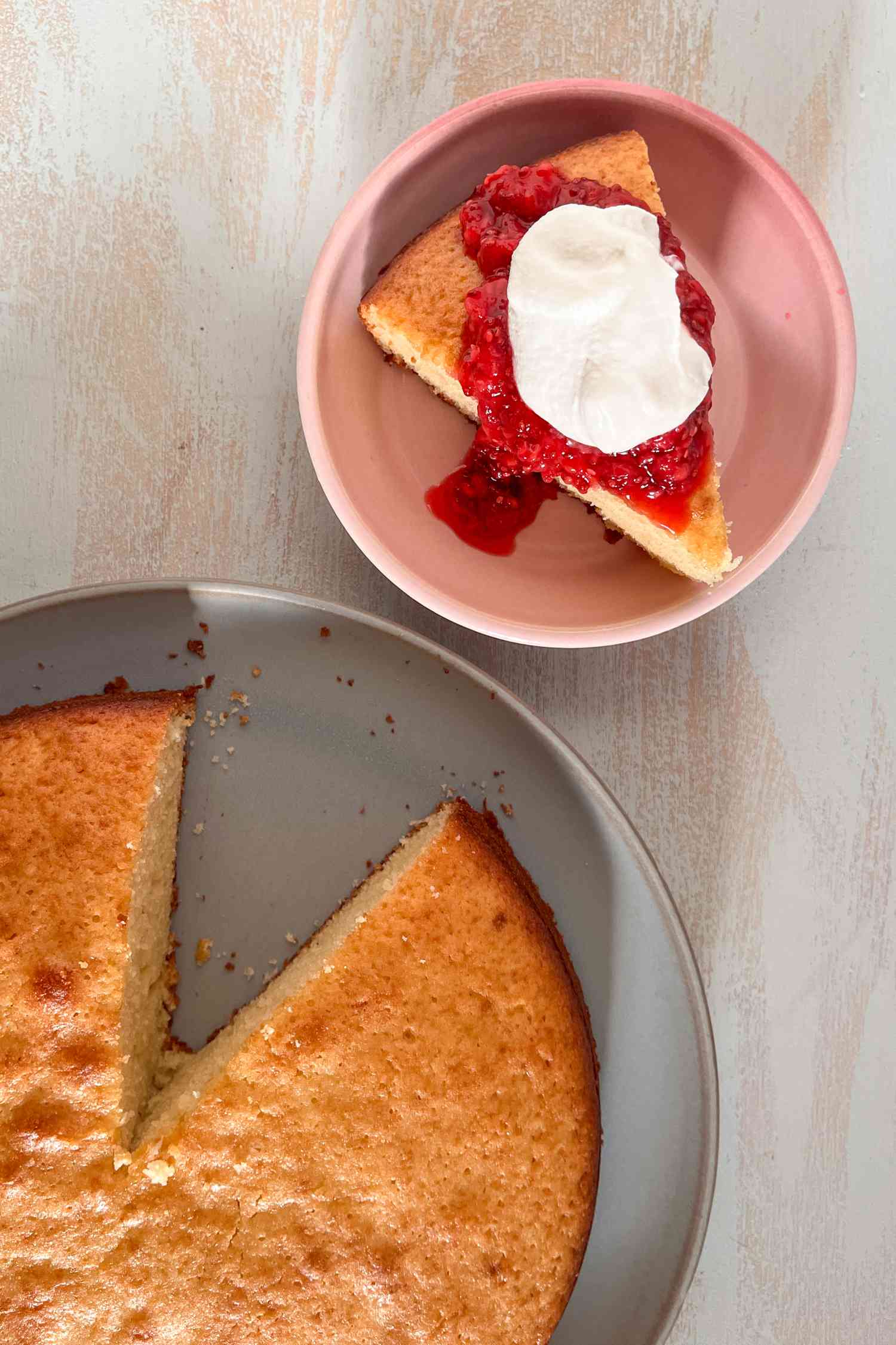 Vue de dessus : tranche de gâteau au yaourt français sur une assiette avec sauce framboise et crème fouettée, et plus de gâteau sur une assiette à côté