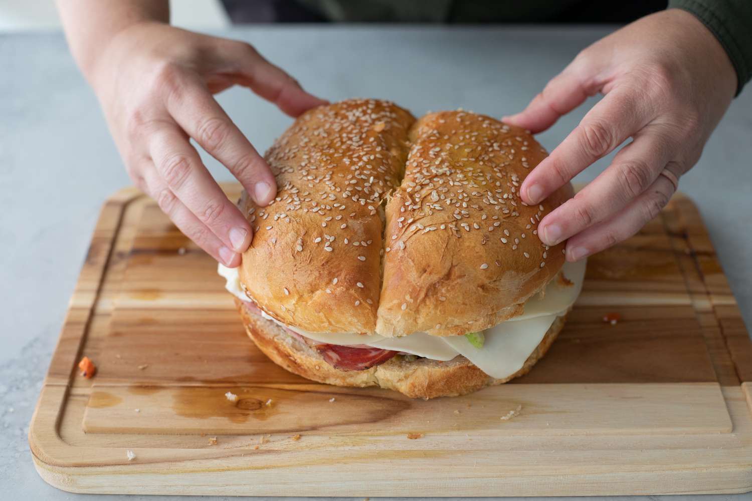 Top Half of Bread Added to Muffuletta on a Cutting Board 