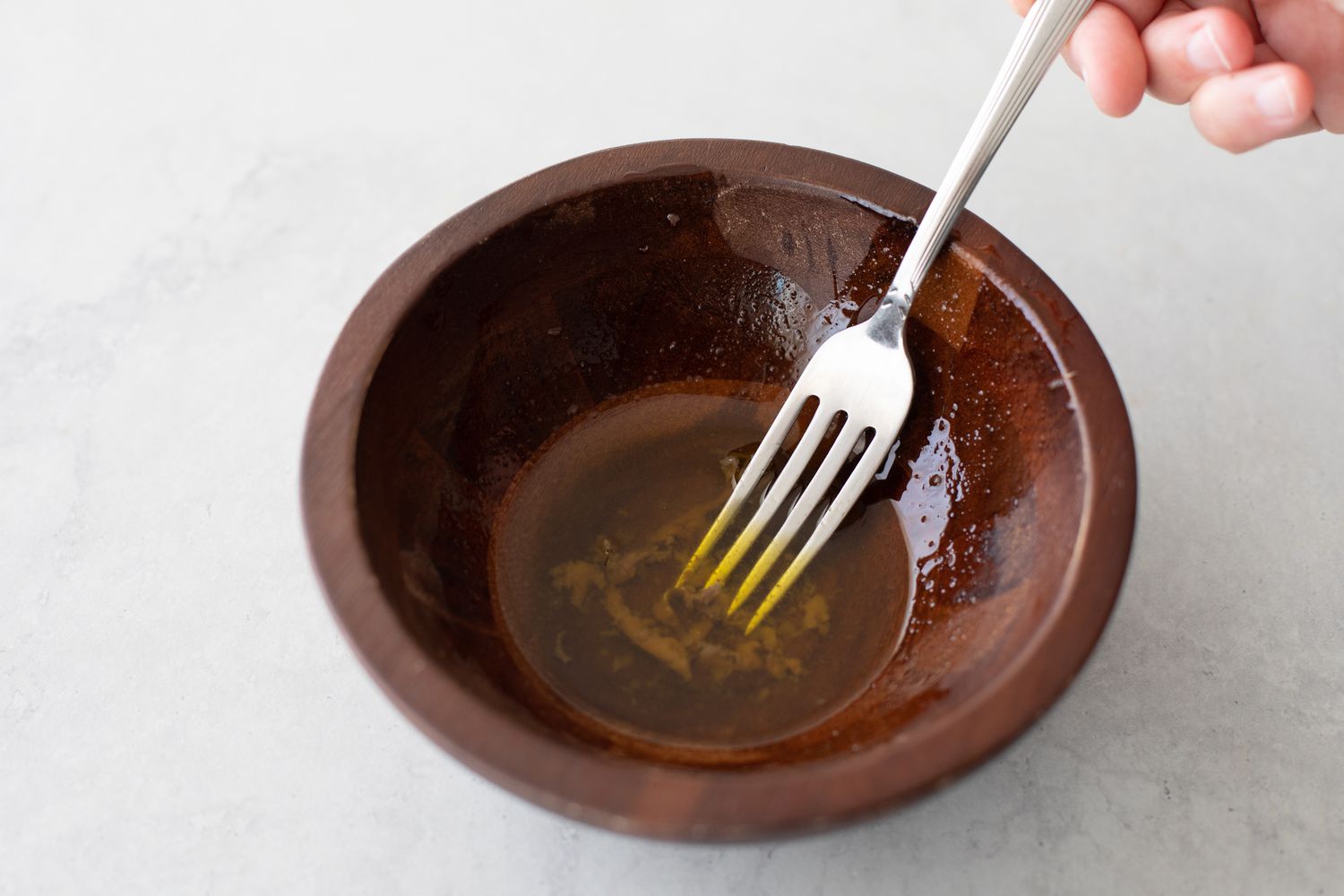 Mash Anchovies in a Wooden Bowl with a Fork for Classic Muffuletta Sandwich Recipe