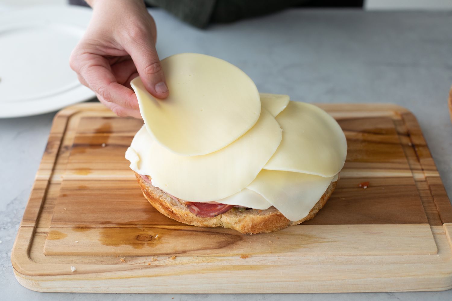 Cheese Added to Classic Muffuletta on a Cutting Board