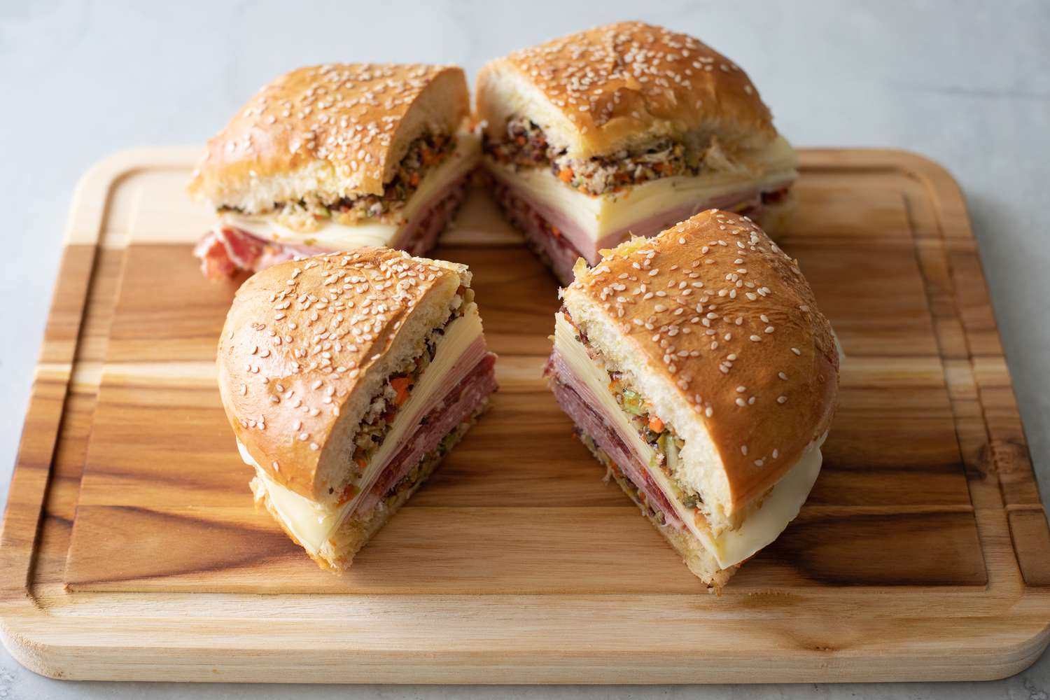 Classic Muffuletta Cut into Quarters on a Cutting Board 