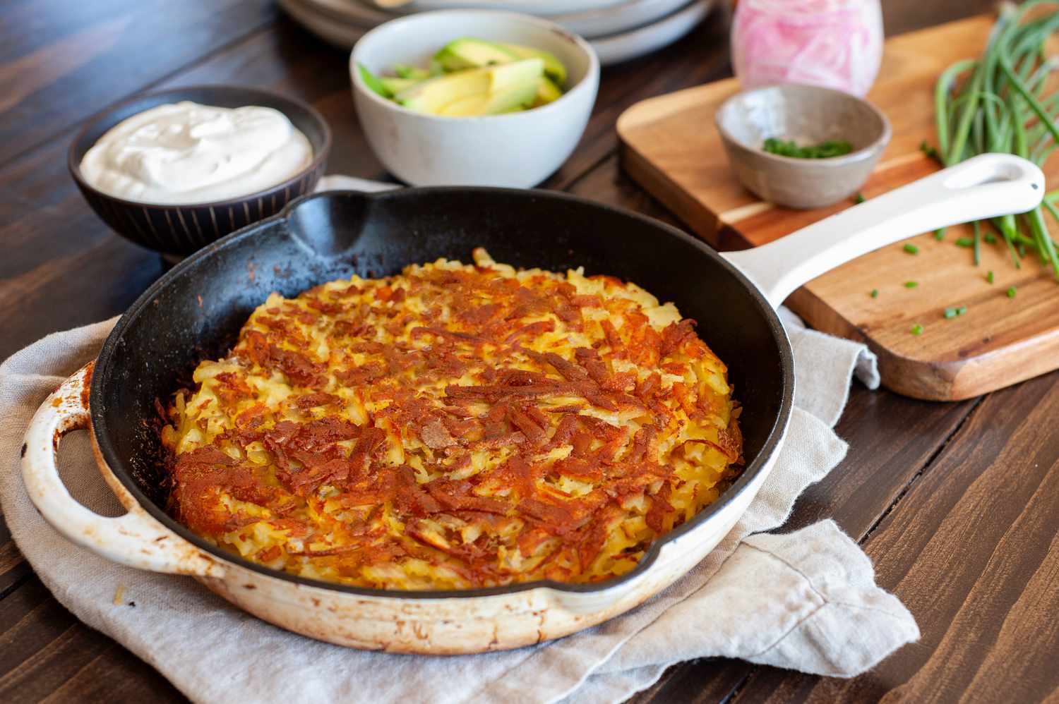 Rösti dans une Poêle Entouré de Bols de Crème Aigre, Avocat et Herbes