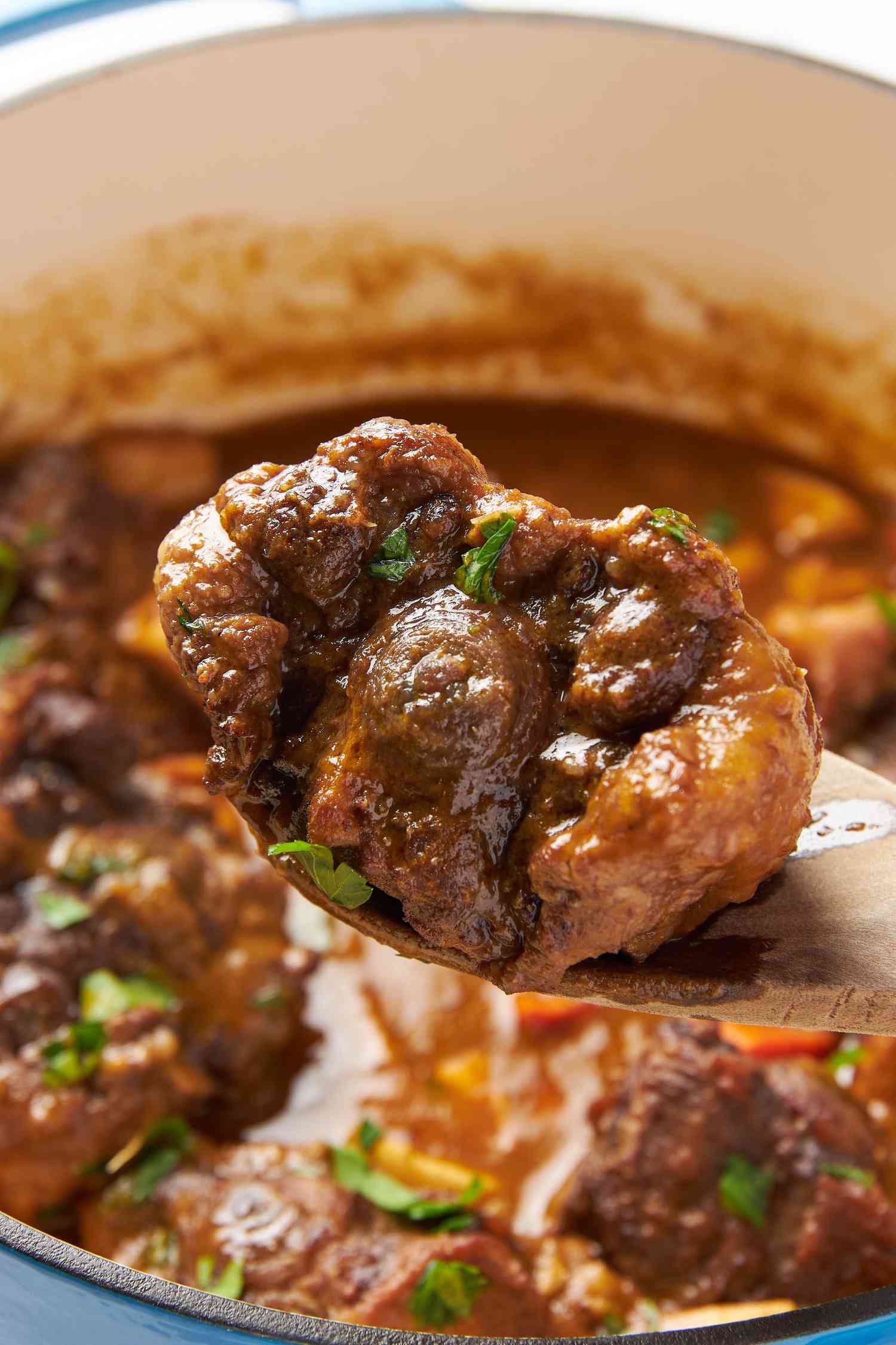 Gros plan sur une cuillère de service avec une queue de bœuf braisée prélevée d'un pot de ragoût de queue de bœuf