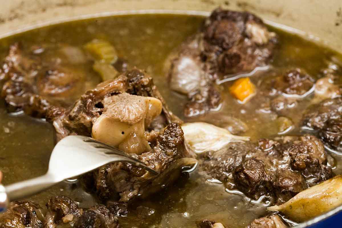 Queues de bœuf cuites avec de l'ail, bouillon, vin, feuilles de laurier, thym et sel