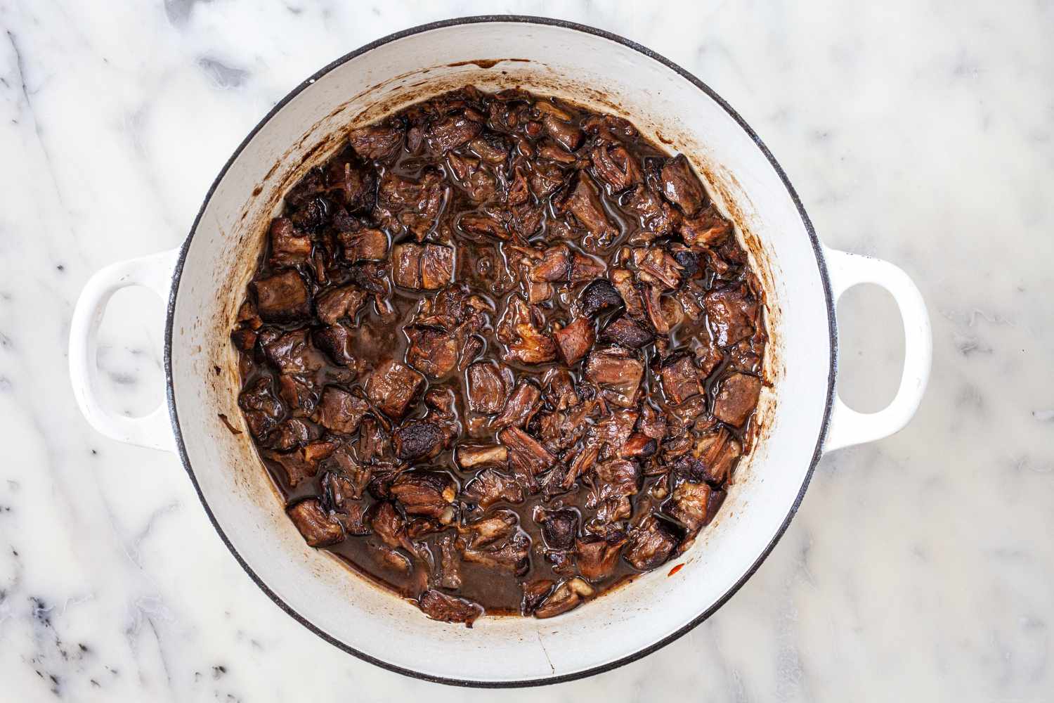 Vue aérienne de queues de bœuf braisées dans une cocotte.