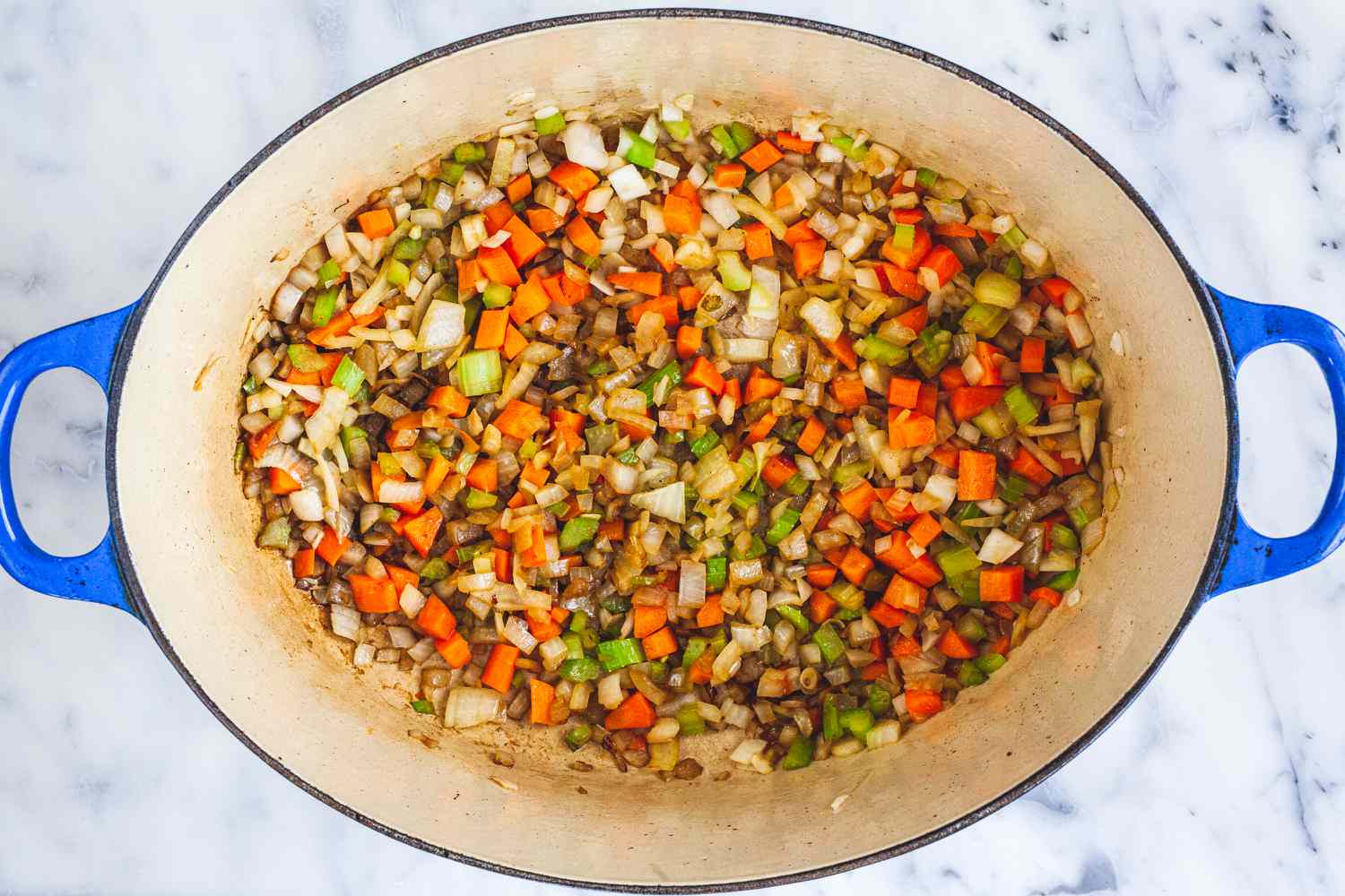 Carottes, céleri et oignon hachés dans une cocotte pour une recette de queue de bœuf.