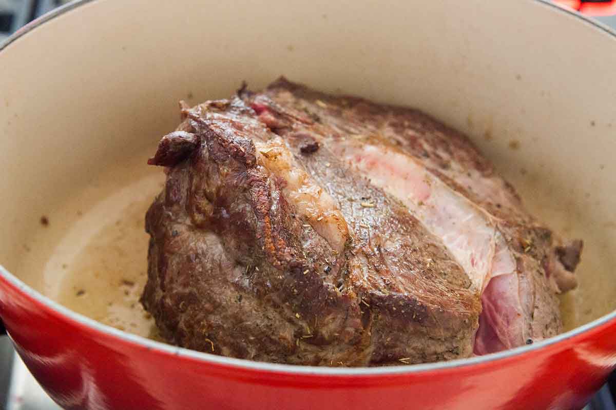 Dorrure d'épaule de bœuf cuisant dans une cocotte en fonte