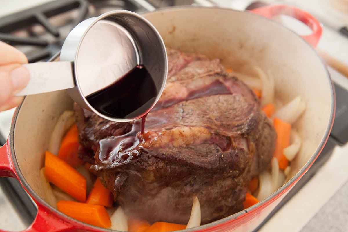 Assaisonnement de viande pour pot-au-feu dans une cocotte avec des carottes et des oignons