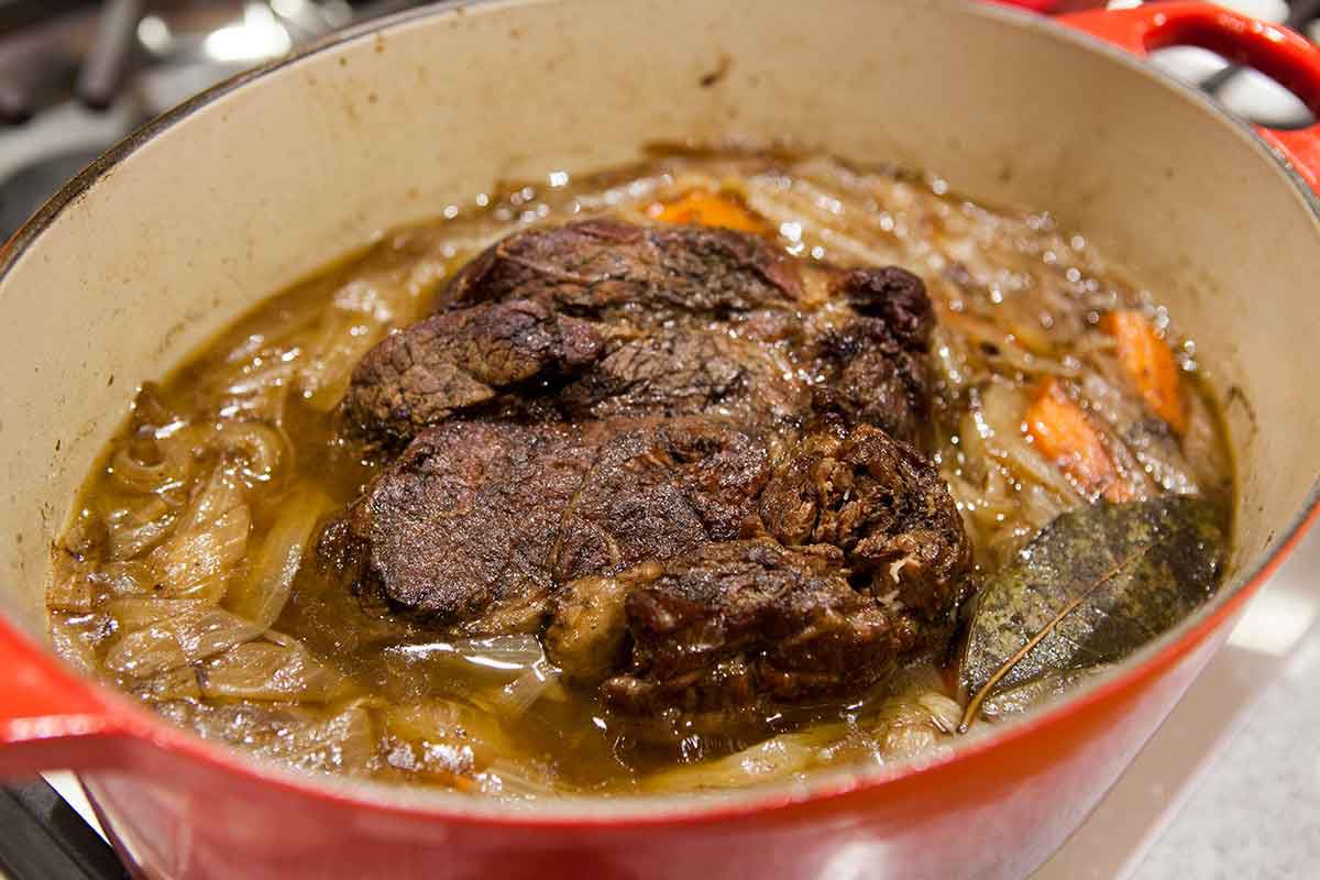 Pot-au-feu de bœuf mijotant dans une casserole sur la cuisinière dans un liquide