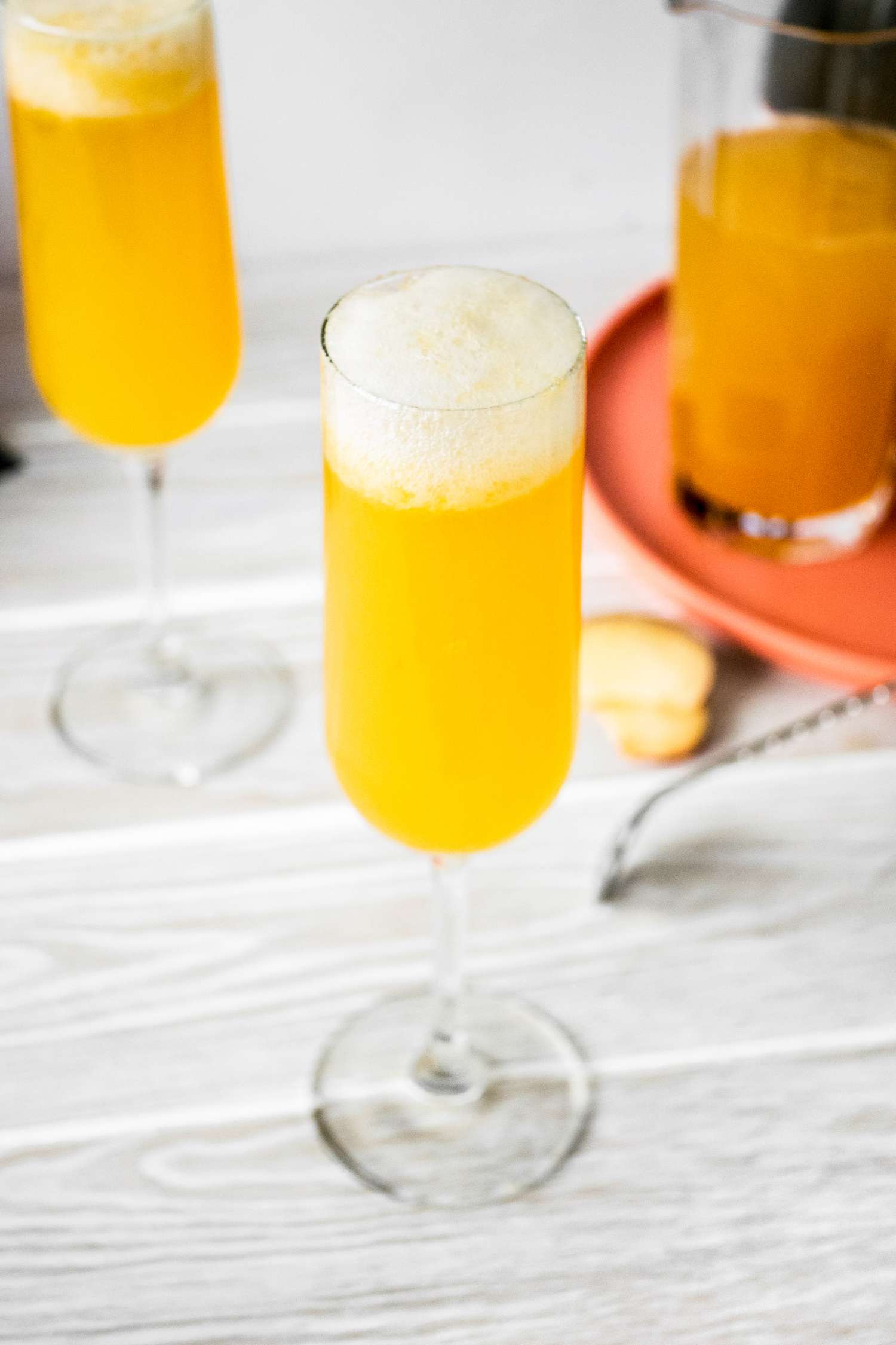 Flûte de cocktail Bellini à la pêche à côté d'un pichet et d'une autre flûte de Bellini