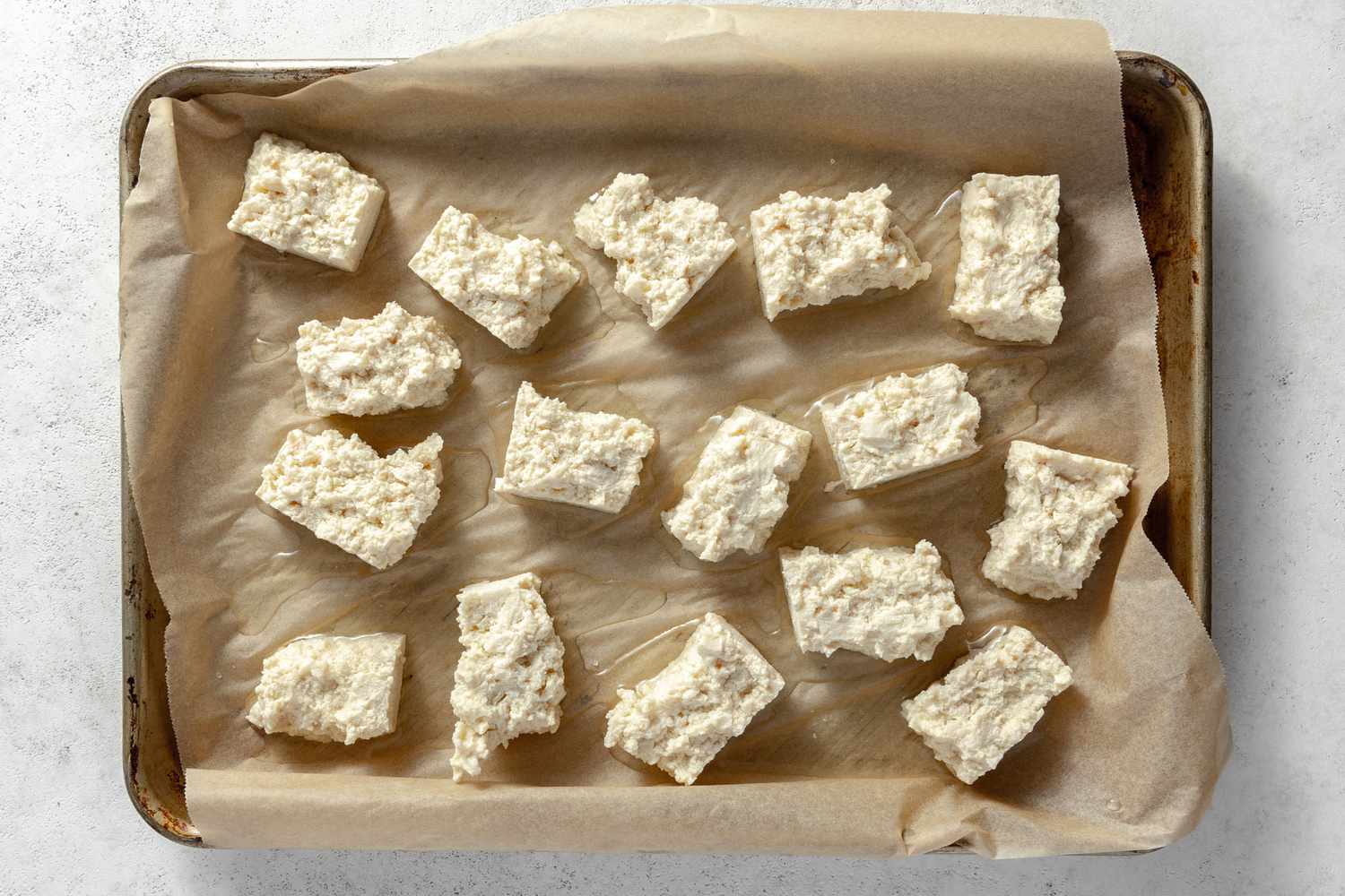 Defrosted Tofu Pieces on a Parchment Lined Baking Pan for Nuggets Vegan Recipe