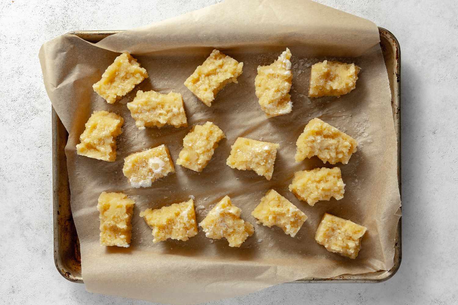 Tofu Pieces on a Parchment Lined Baking Pan after Freezing in Refrigerator for Vegan Nuggets Recipe