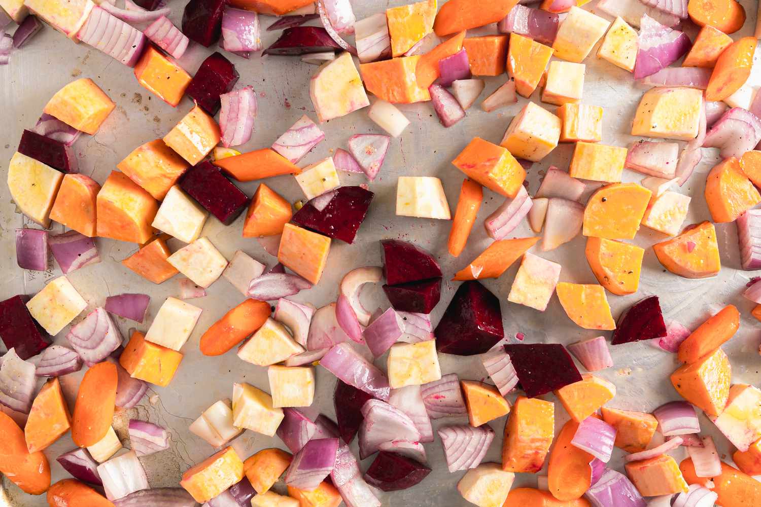 Seasoned Roughly Cubed Red Onion, Carrots, Parsnips, Sweet Potatoes, and Beets on a Baking Tray for Root Vegetable Panzanella Recipe