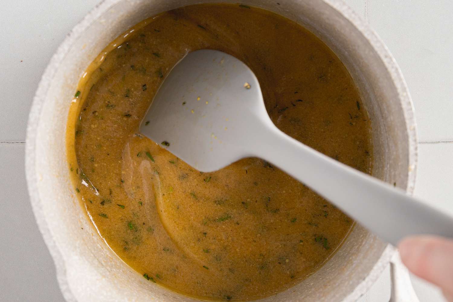 Herbs Mixed into Pot of Brown Butter Dressing Using a Spatula