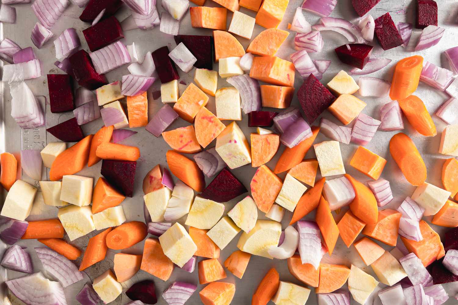 Roughly Cubed Red Onion, Carrots, Parsnips, Sweet Potatoes, and Beets on a Baking Tray for Root Vegetable Panzanella Recipe