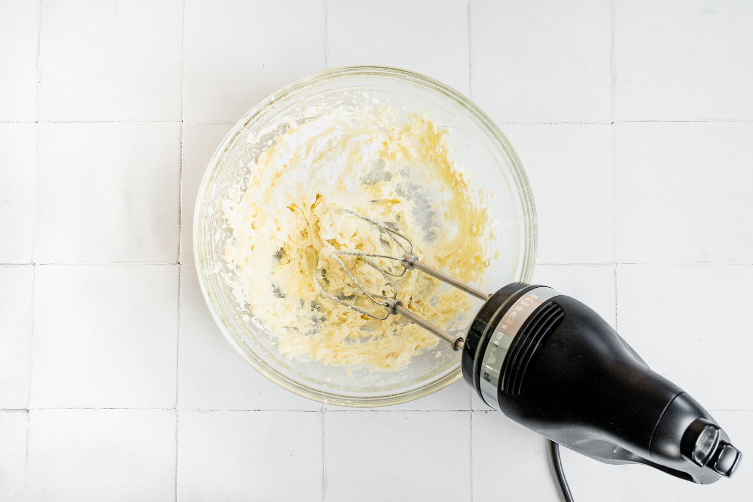 Bowl of Whipped Cream Cheese Using a Hand Mixer for Dirt Cake with Gummy Worms