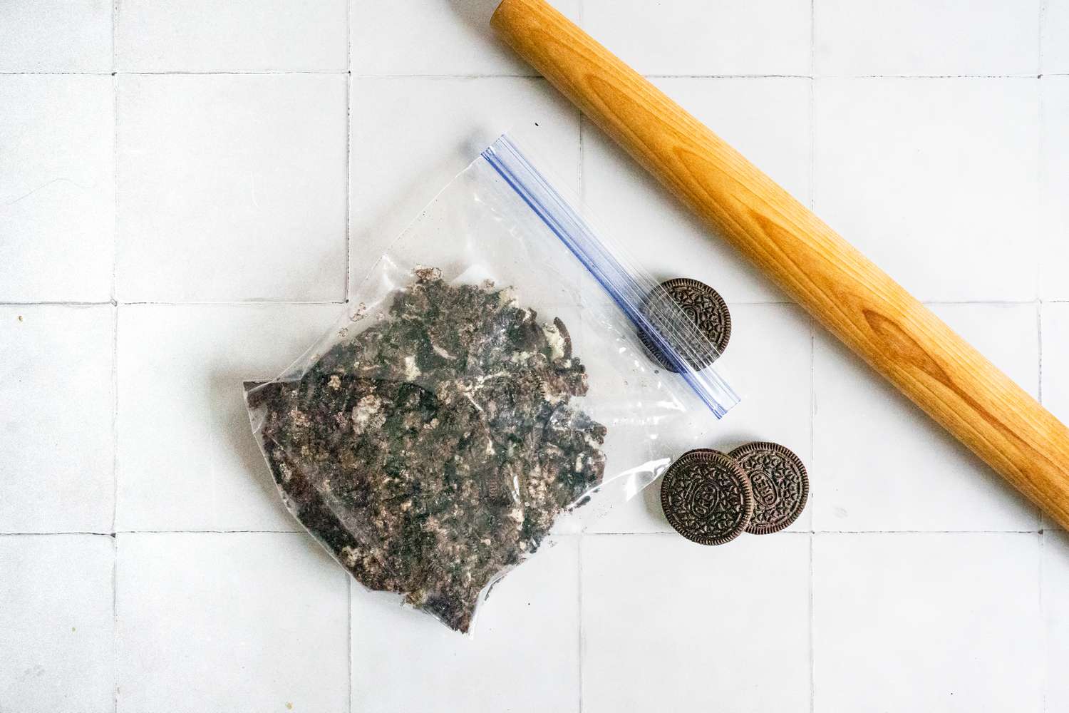 Bag of Crushed Oreos Next to a Rolling Pin and Uncrushed Oreos for Dirt Cake Recipe