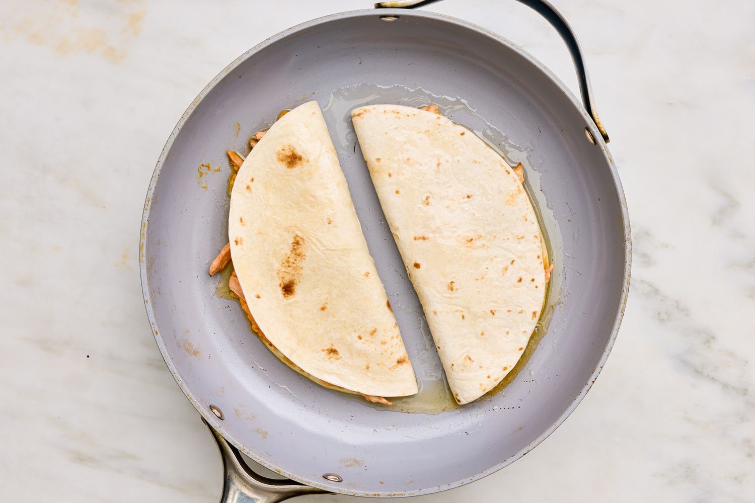 Ajout d'huile dans la poêle avec des quesadillas au poulet buffalo