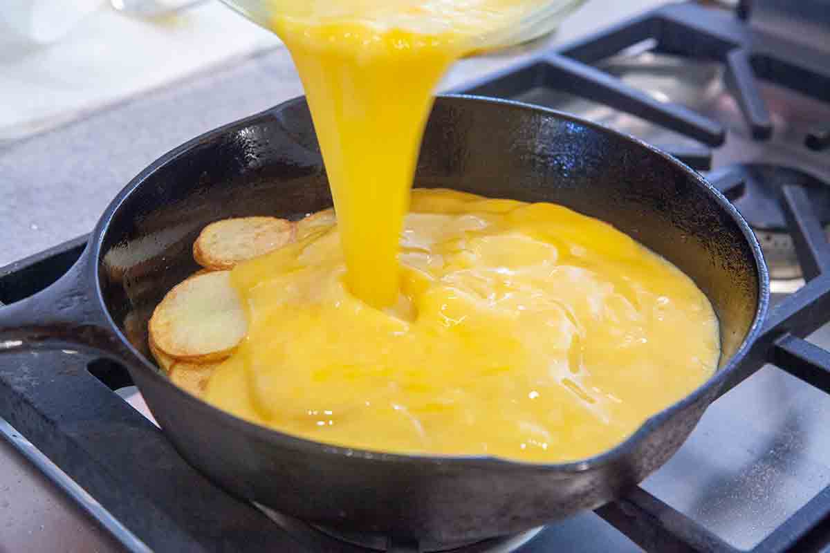 verser le mélange d'œufs sur les pommes de terre pour la tortilla espagnole