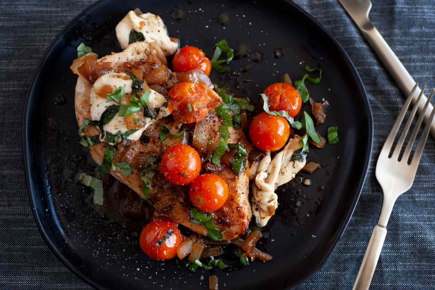 Poulet caprese sur un plateau noir.