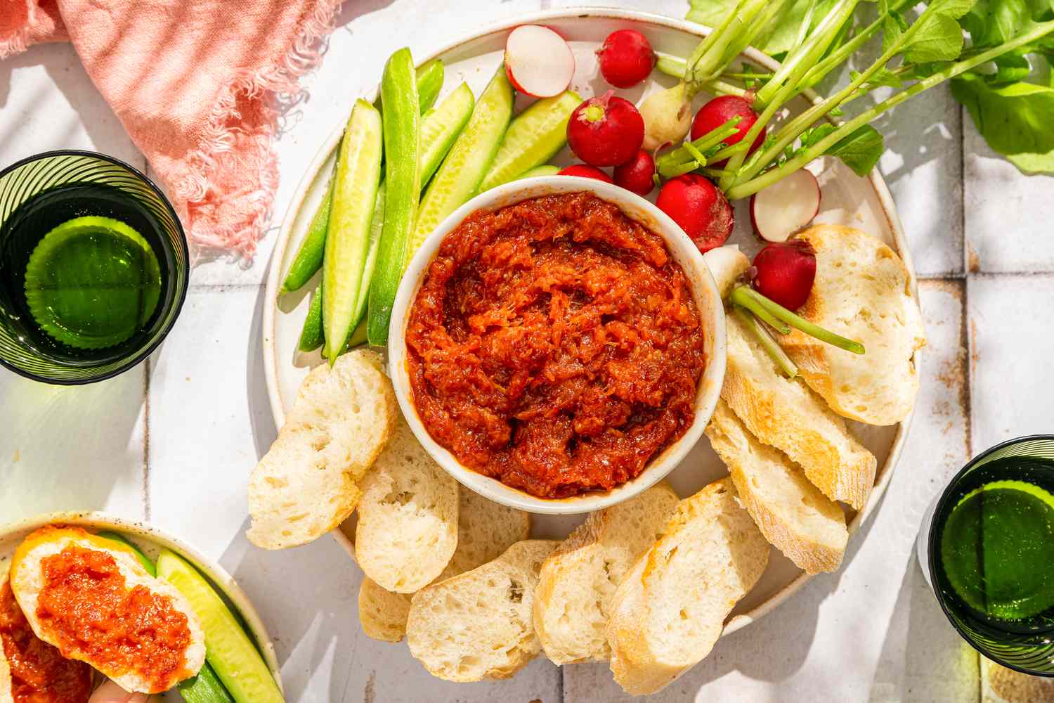 Overhead view of 2-ingredient honey chorizo spread in a bowl surrounded by radishes, cucumber spears and sliced baguette