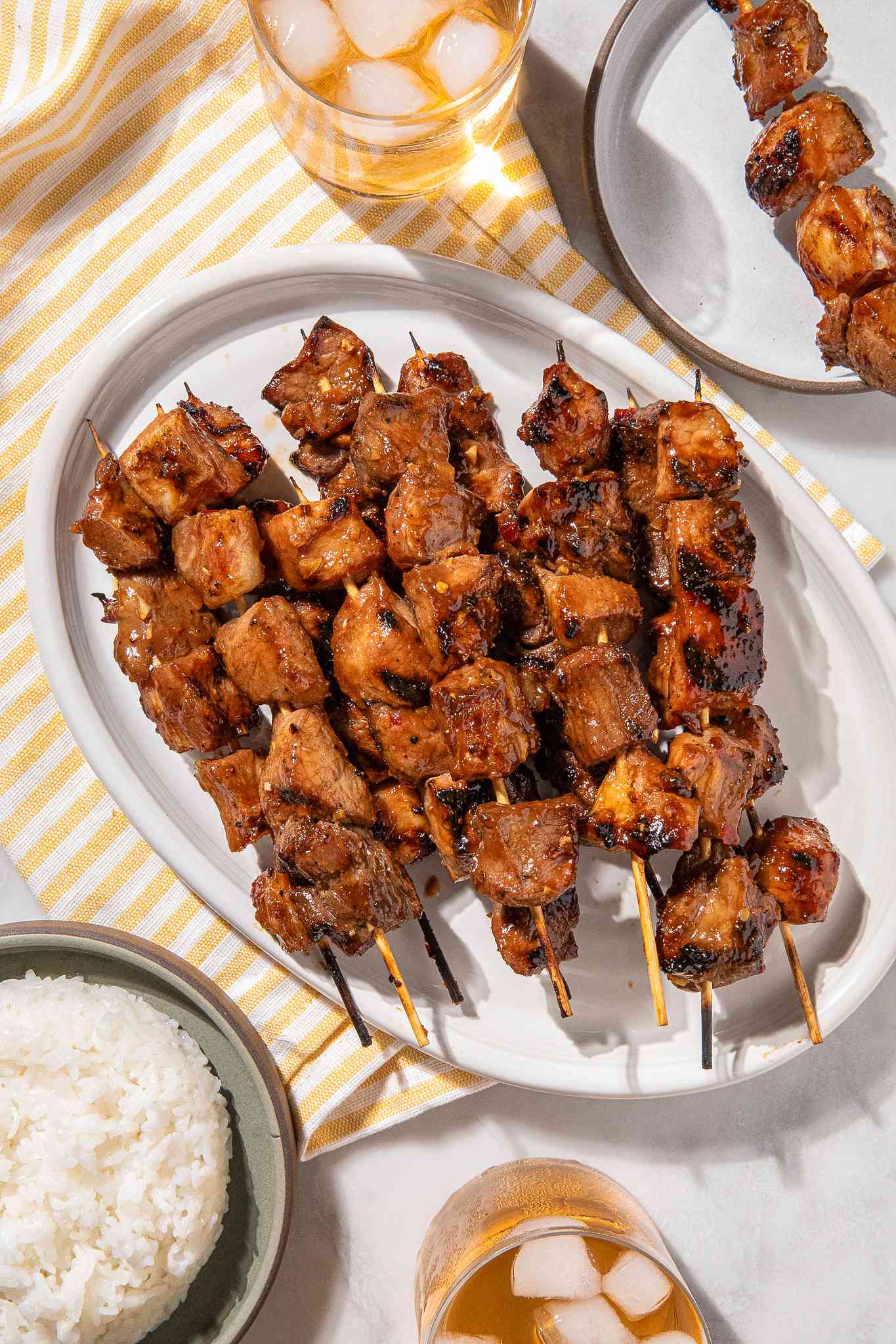 Brochettes de porc grillées sur un plat blanc avec du riz à côté