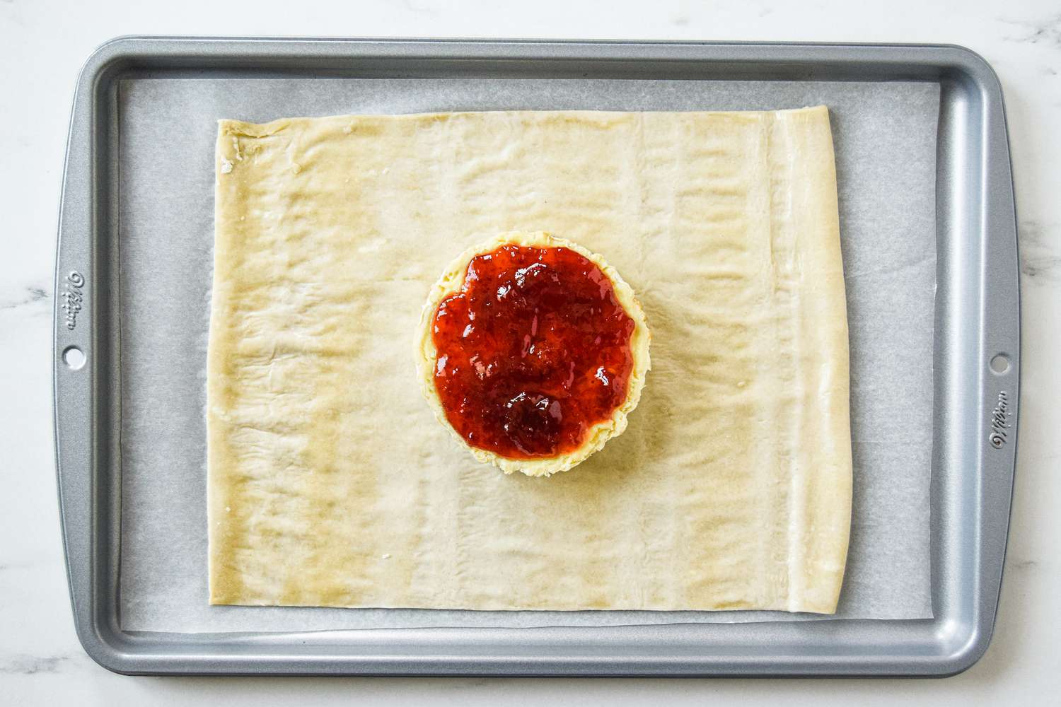 Confiture sur le fromage brie posé sur de la pâte feuilletée pour faire du brie au four