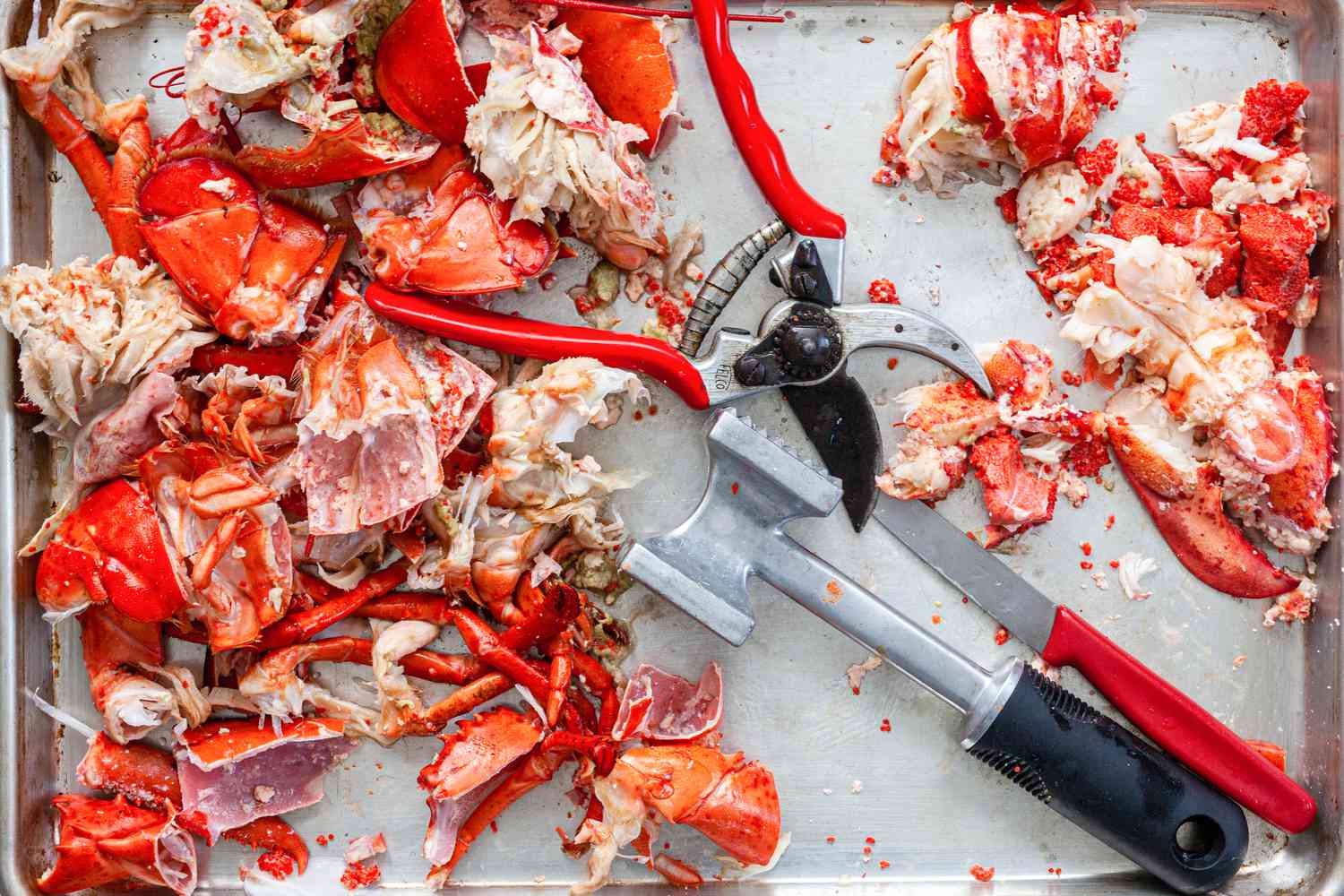 Homard décortiqué à l'aide d'un maillet, de ciseaux et d'un couteau dans un plat de cuisson pour la bisque de homard