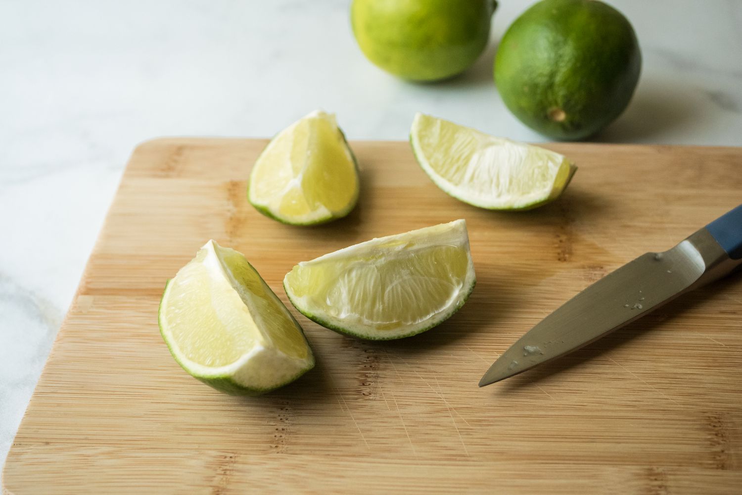 Quartering limes to make a sweet and puckery cocktail