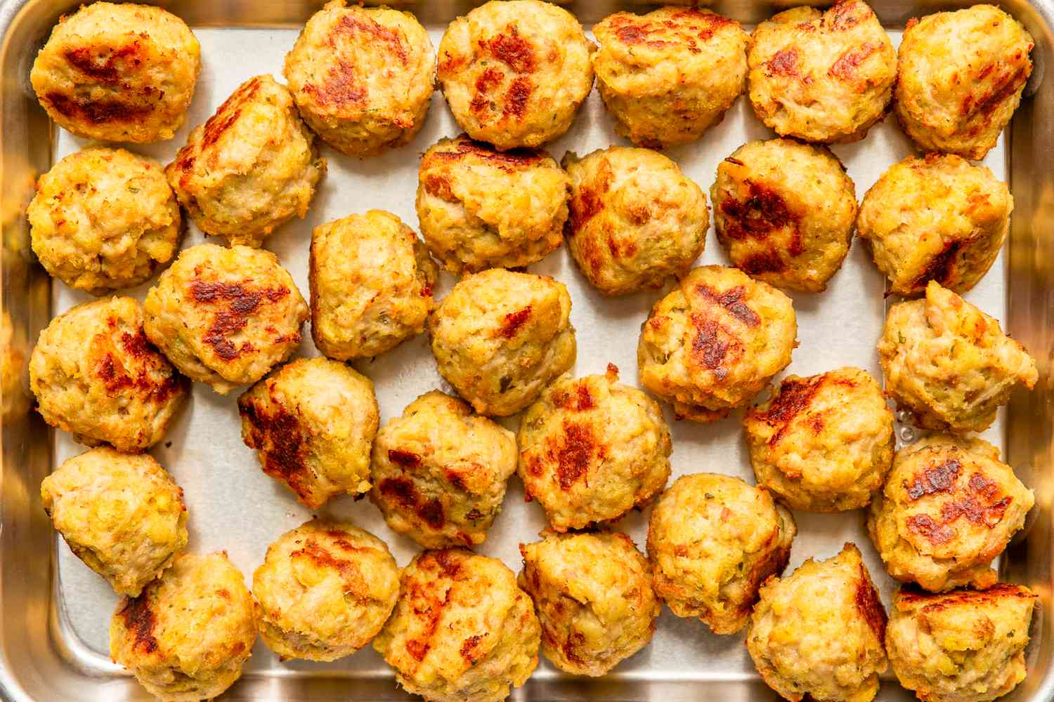 Vue aérienne d'une plaque de cuisson en métal pleine de boulettes de poulet à 3 ingrédients